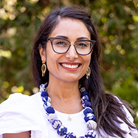 Veena Dubal - smiling wearing glasses with long dark haired wiman