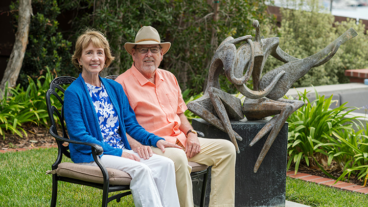 man and woman sit on bench in a garden