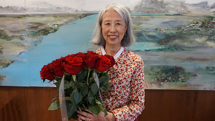 smiling woman with grey hair holds bouquet of red roses