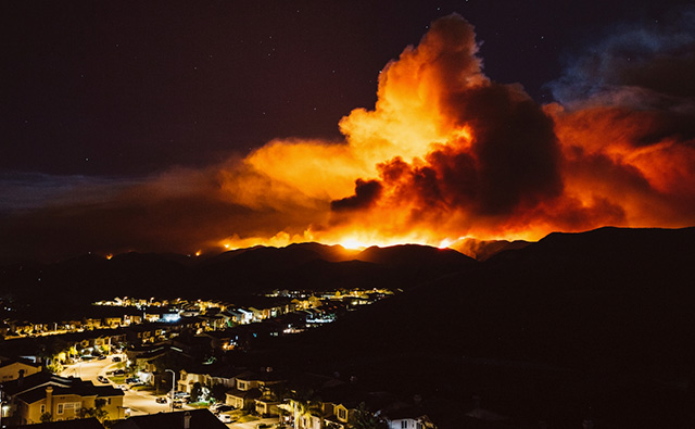 A California wildfire burns near a residential area at night