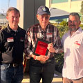 three men, one holds award