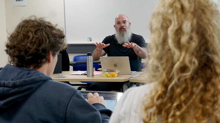 man with beard and glasses speaks to students