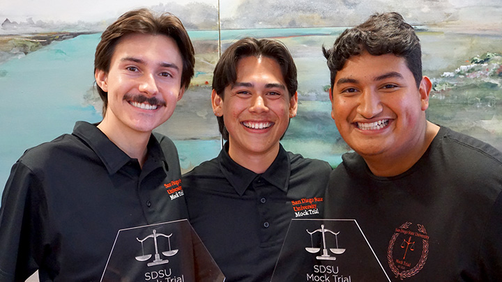 three male students smiling, 2 hold awards