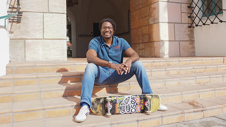 Man sites with skateboard on SDSU campus