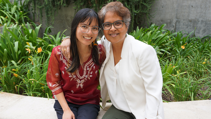 two women smiling women site, one has arm around the other