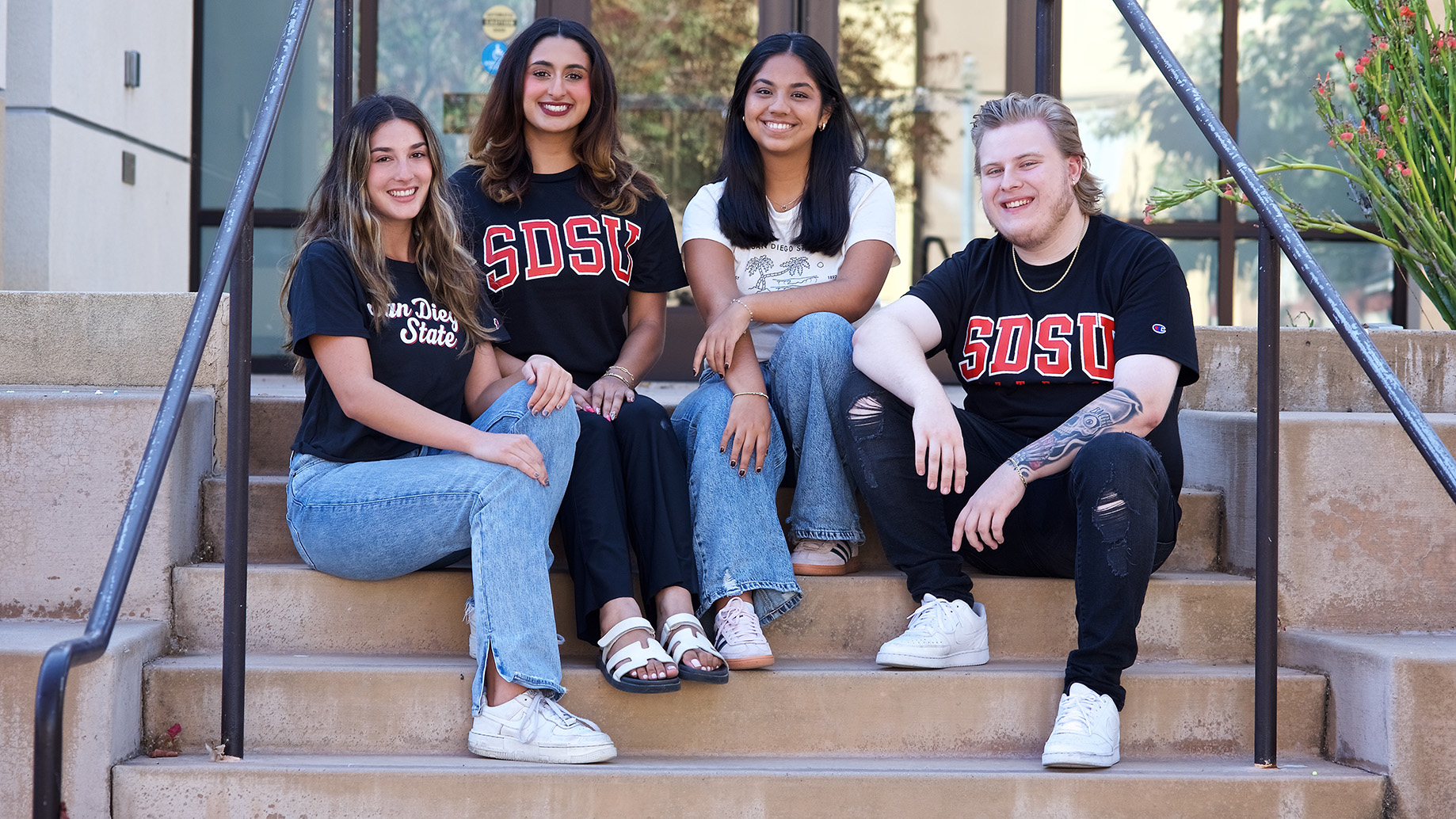 4 students sit on steps