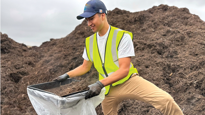man screening dirt in compost pile