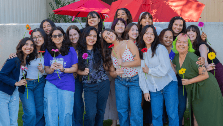 group of women smiling and holding daisies